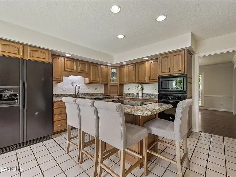 Kitchen with island seating, granite counters, and warm cabinetry at 11016 Calloway View Dr